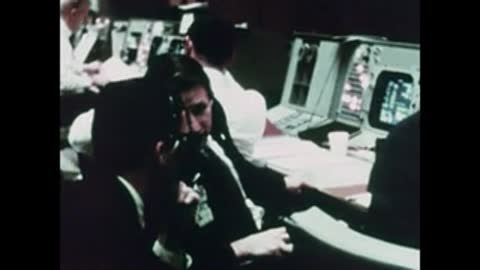 Close-up of technicians in uniform conferring inside the control room