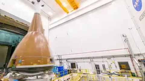 Orion spacecraft inside large NASA acoustic test chamber with equipment around it