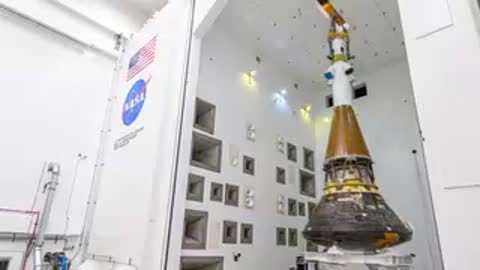 Technicians on cherry picker working on top of Orion spacecraft stack in chamber