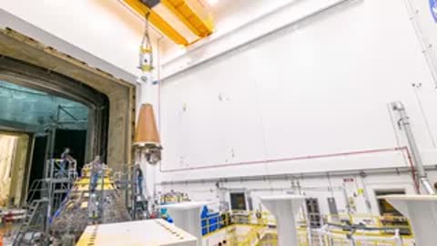 Overhead crane lifts components over the Orion capsule in the facility.