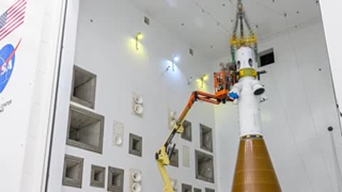 Technicians working around the Orion spacecraft mounted in the testing area.