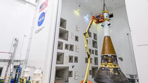 Hydraulic lifts position workers near the Orion capsule for integration work.