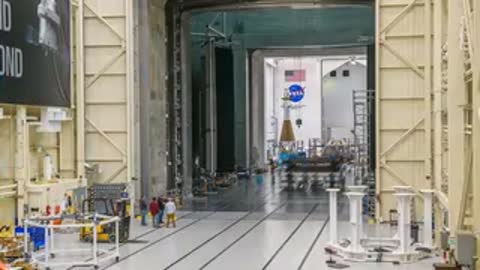 Crane system moving heavy structural components across the large test hall.