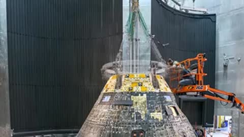Engineers perform maintenance and alignment tasks on the Orion module.