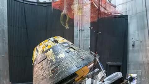 Orange safety net lowered over the Orion capsule during a drop test simulation.