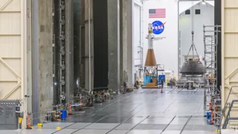 Orion spacecraft moved across the large assembly floor via overhead crane.