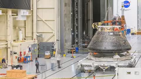 Technicians working around the Orion module on a transport platform.