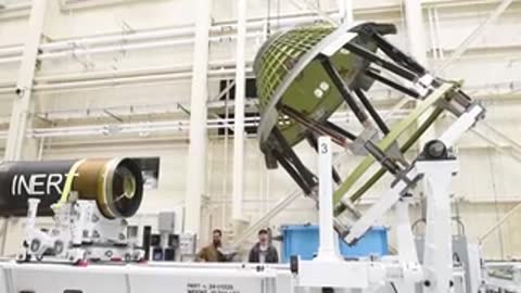 Technicians working on spacecraft structure components in large assembly facility