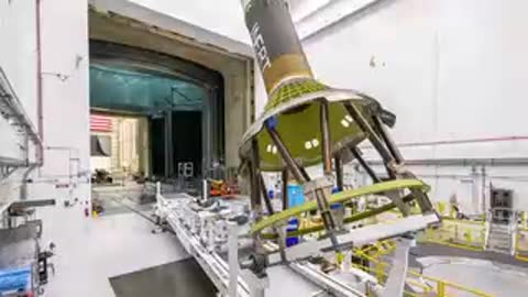 Medium shot of metal framework structure being tilted by crane in large hangar