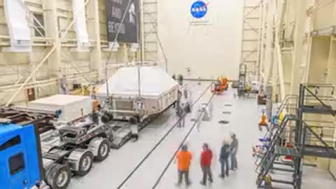 Wide shot of crane lifting large white crate container inside large warehouse