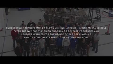 Wide shot of large group of people posing inside hangar with text overlay