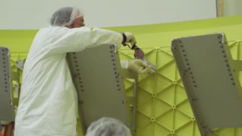 A technician working on a panel attachment inside a workshop.