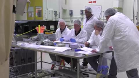 A team of engineers reviewing documents around a table in a workshop.