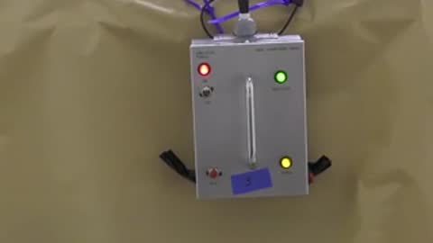 A grey electronic testing box mounted on a tent wall with blinking status lights.