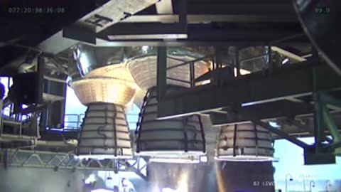 Close-up view underneath a rocket structure during an engine test firing.