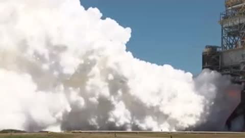 Heavy smoke billowing from a rocket test stand structure during a test fire.