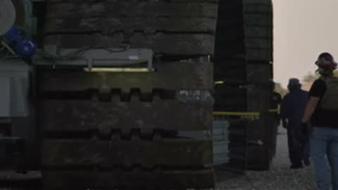 Close-up of crawler treads rolling over dirt path during transit.