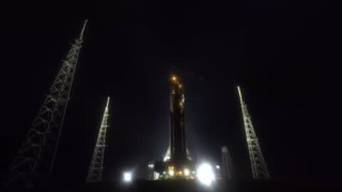 Nighttime view of illuminated launch pad with towers and stacked SLS.
