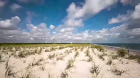 Wide landscape view of coastal dunes with SLS visible in distance.