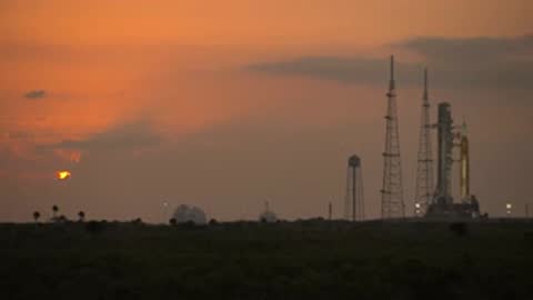 Sunrise view of SLS silhouette on launch pad with orange sky.