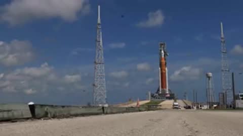 Daytime wide shot of SLS on launch pad with clear blue sky.