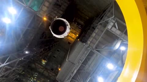 Overhead view of lowering a large cylindrical component into place in the Vehicle Assembly Building.