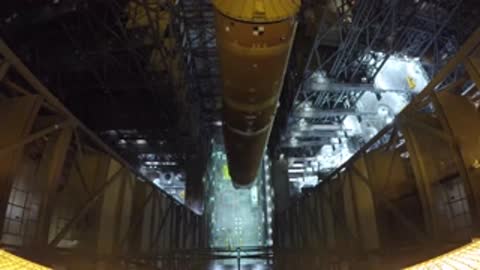 Overhead view of the large core stage being slowly lowered vertically into the VAB structure.