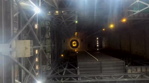 Looking down a long industrial hallway with structural framing and warm lights.