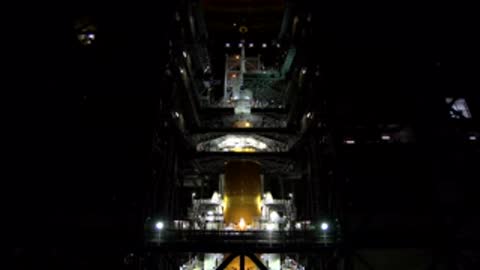 A view of the interior of a tall industrial facility with bright overhead lights.
