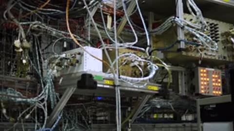 A complex array of electronic equipment and wiring is mounted on a rack.