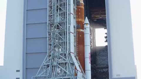 Close-up view of rocket base emerging through large VAB doorway.