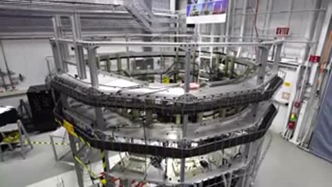 A circular multi-level engineering test structure is shown in a large testing facility.