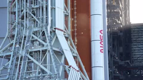 Medium shot of the orange core stage and white booster ascending slowly.