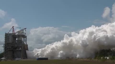 Exterior wide shot showing plumes of thick white smoke drifting away from the test stand.