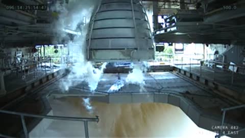 Interior view of a test stand after engine shutdown, with lingering smoke and steam.