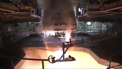Interior view showing the active RS-25 engine firing with bright orange flames.