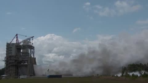 Wide exterior shot of the test stand surrounded by smoke and landscape.