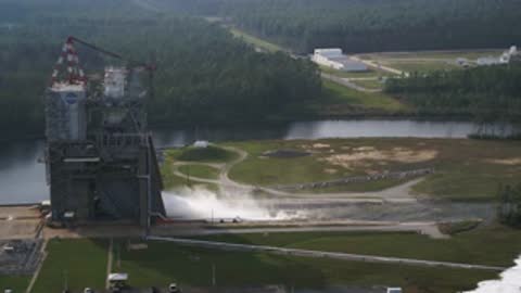 Wide shot of a rocket engine testing facility during a static test.