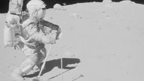 Archival footage of an astronaut kneeling and working on the lunar surface.