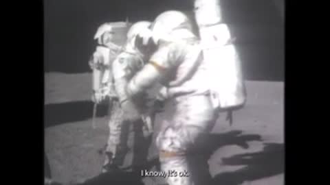 Archival footage of two astronauts interacting on the lunar surface.