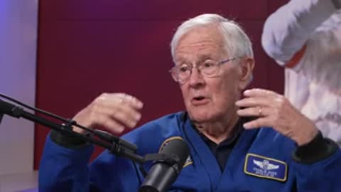 Man in blue shirt speaking in studio with microphone.