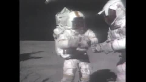 Astronauts interacting in black and white moon footage.