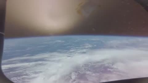 View of Earth's horizon and cloud cover from spacecraft window.