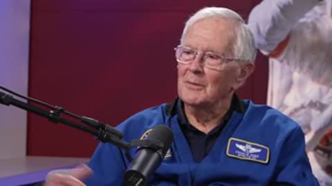 An elderly man speaking animatedly with hand gestures in an interview