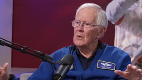 An elderly man talking and gesturing with hands in an interview