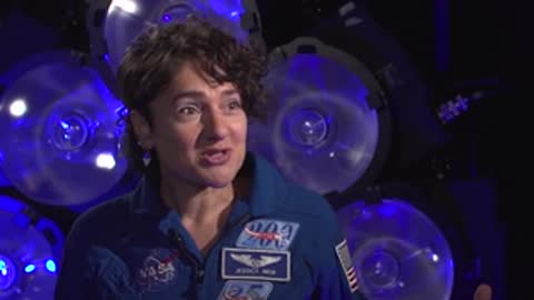 A woman in a blue NASA jumpsuit speaking during an interview