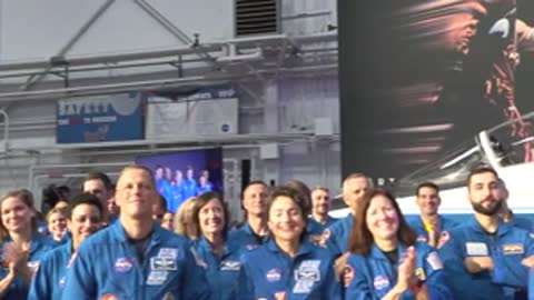 A large crowd of people in blue uniforms applauding in a facility