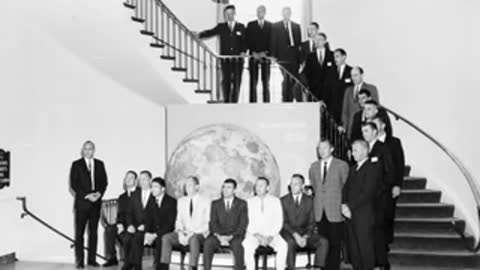 Historical black and white group portrait of early NASA astronauts and officials