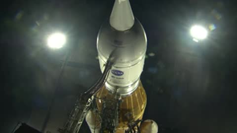 A close-up view of a rocket nose cone illuminated by bright lights at night.