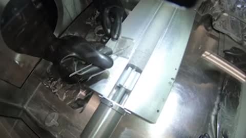 A close-up view of robotic arms manipulating a mechanism inside a cleanroom chamber.